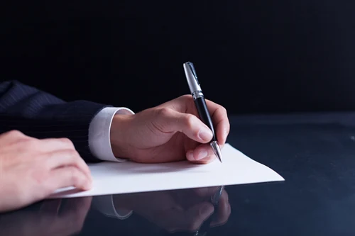 Dłoń zapisująca informacje na kartce — zdjęcie ilustracyjne